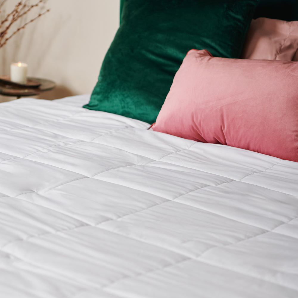 A heated king duvet with a few cushion on the bed.
